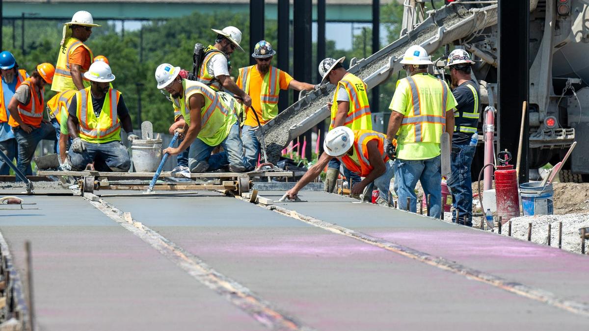 Construction workers smooth cement around newly laid streetcar tracks in Berkley Riverfront Park on Wednesday. The track slab is the first to be poured for the streetcar’s 0.7-mile riverfront extension.