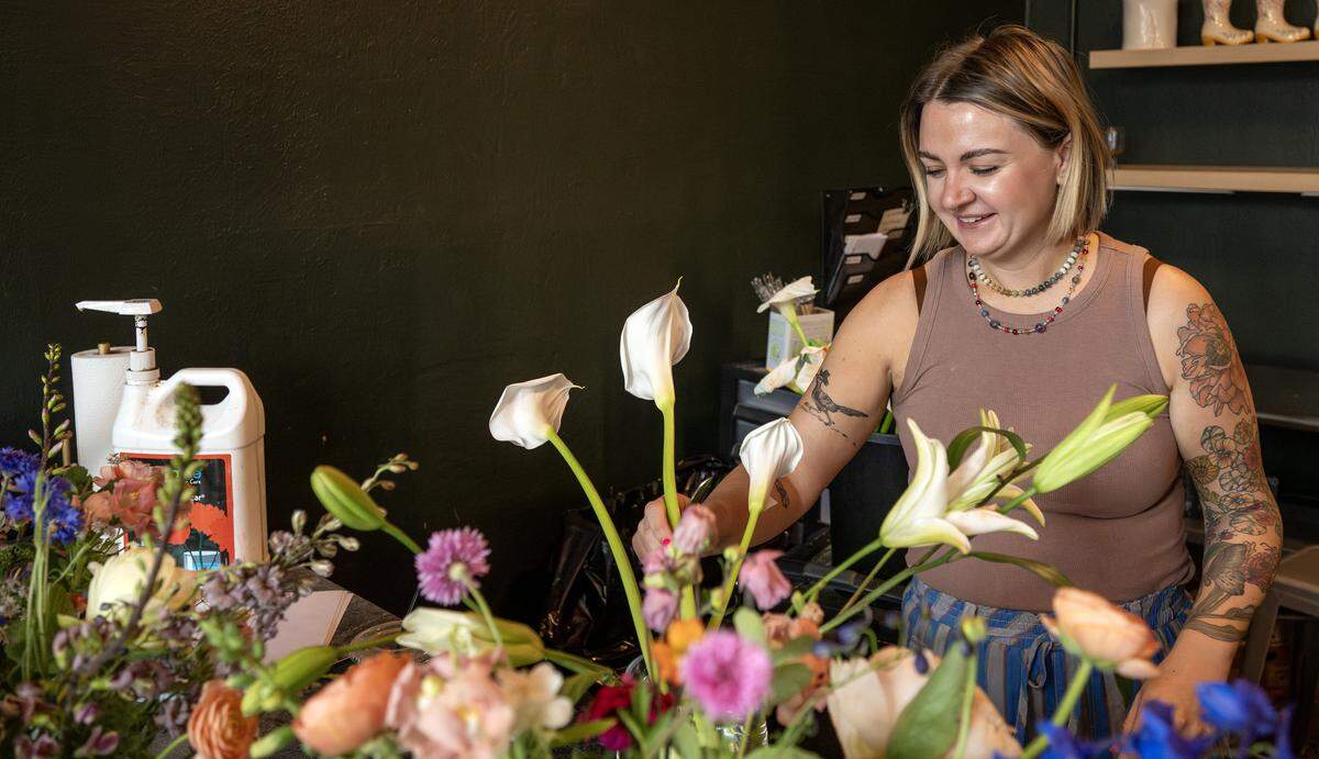 Betsy Ford, co-owner of Lily Floral Collective, arranges flowers into glass vases on Friday, May 8, 2026, in Kansas City.