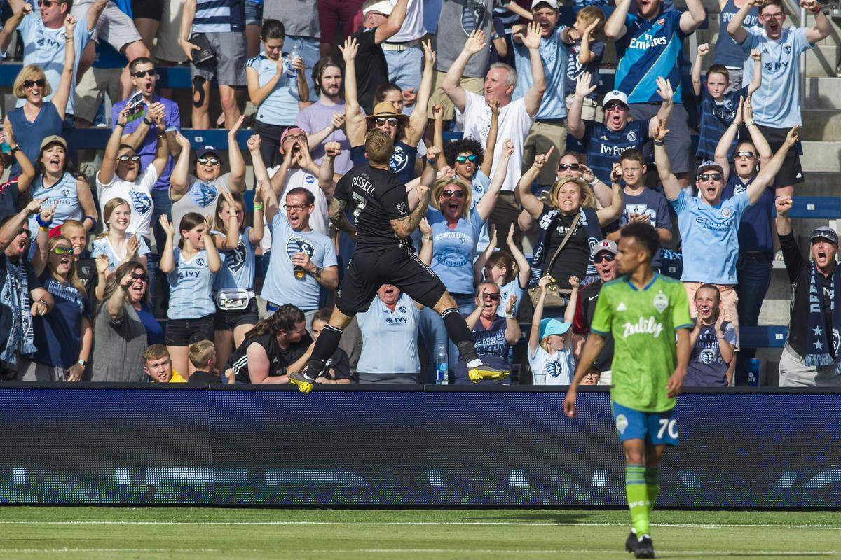 Sporting Kansas City forward Johnny Russell leaps into the air in front of fans in the Cauldron at Children’s Mercy Park.