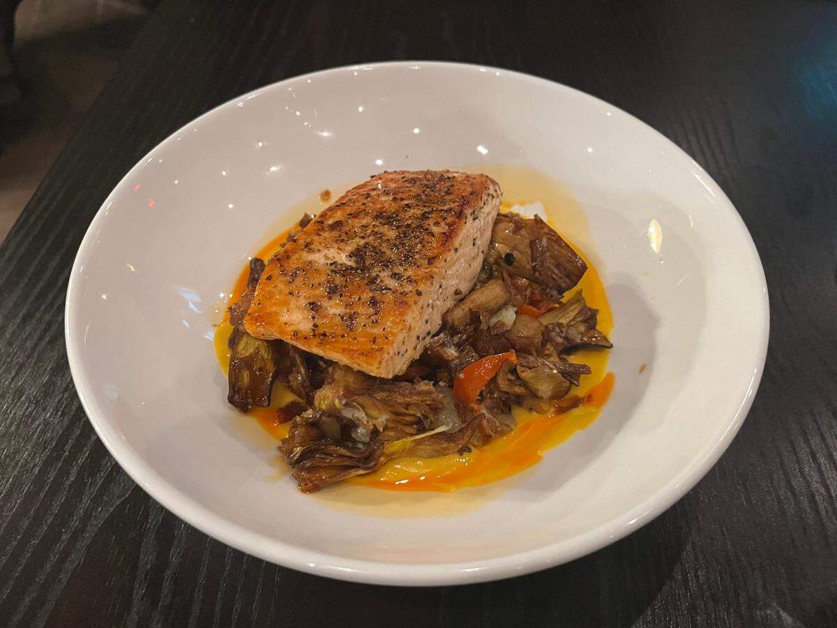 Prima Facie’s roasted salmon is topped with citrus beurre blanc, english peas, crispy bacon, spinach and cannellini beans.