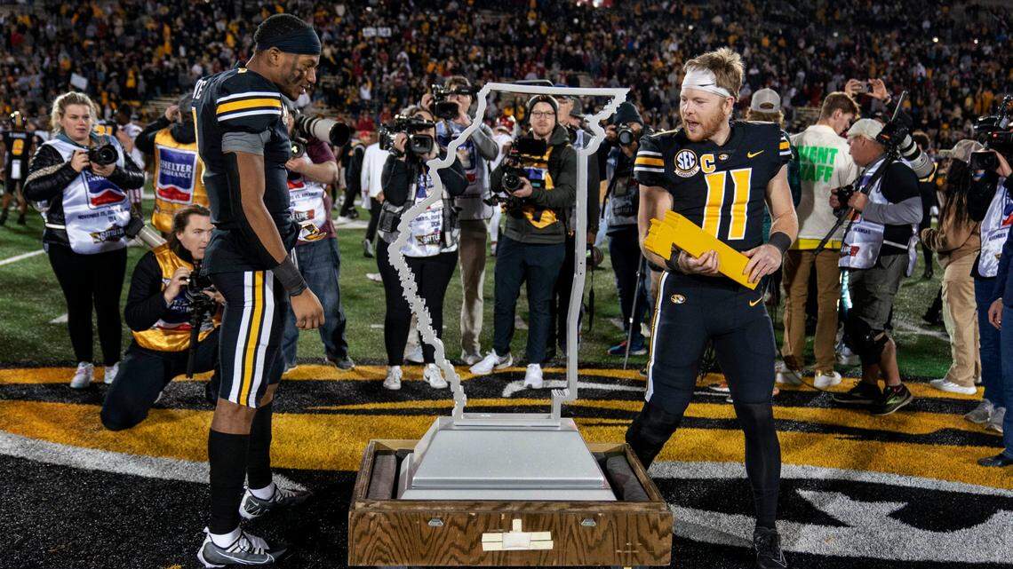 Missouri ‘s Tauskie Dove, left, and Barrett Banister check out the 180-pound Battle Line Trophy after the Tigers defeated Arkansas on Friday in Columbia, Mo.