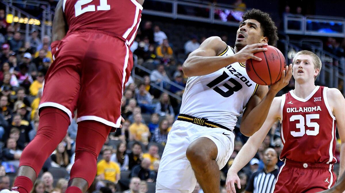 MU’s Mark Smith, middle, got hit with a charging foul while driving into OU’s Kristian Doolittle during the first half of Tuesday night’s Hall of Fame Classic game at the Sprint Center.