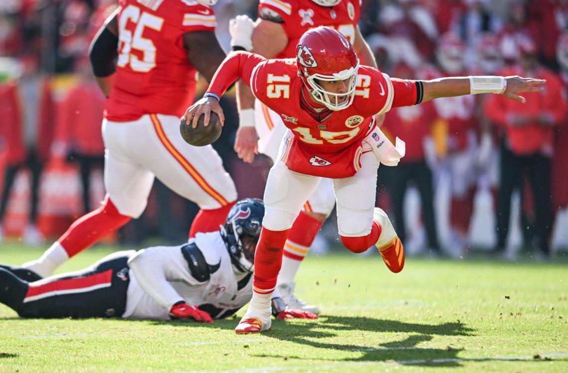 Kansas City Chiefs quarterback Patrick Mahomes (15) breaks free from the grasp of Houston Texans defensive tackle Tim Settle Jr. (98) to run in for a touchdown in the first quarter on Saturday, Dec. 21, 2024, at GEHA Field at Arrowhead Stadium.