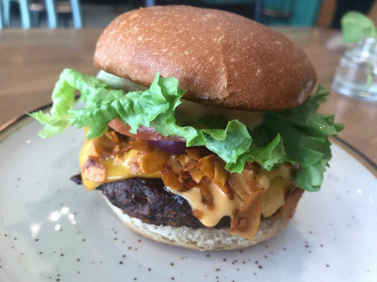 Kind Food’s bestselling Bac’n Mushroom Meta - veggie burger with grilled mushrooms and housemade coconut “bacon,” lettuce, tomato, red onion and sauce.