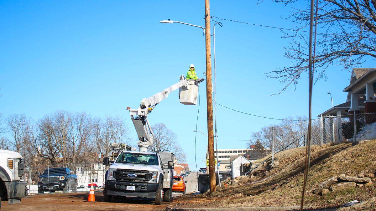 A Comcast Xfinity worker restores a power cable in the 520 block of South Osage Street in Independence. A water tower being demolished fell on the power lines, damaging them Tuesday.