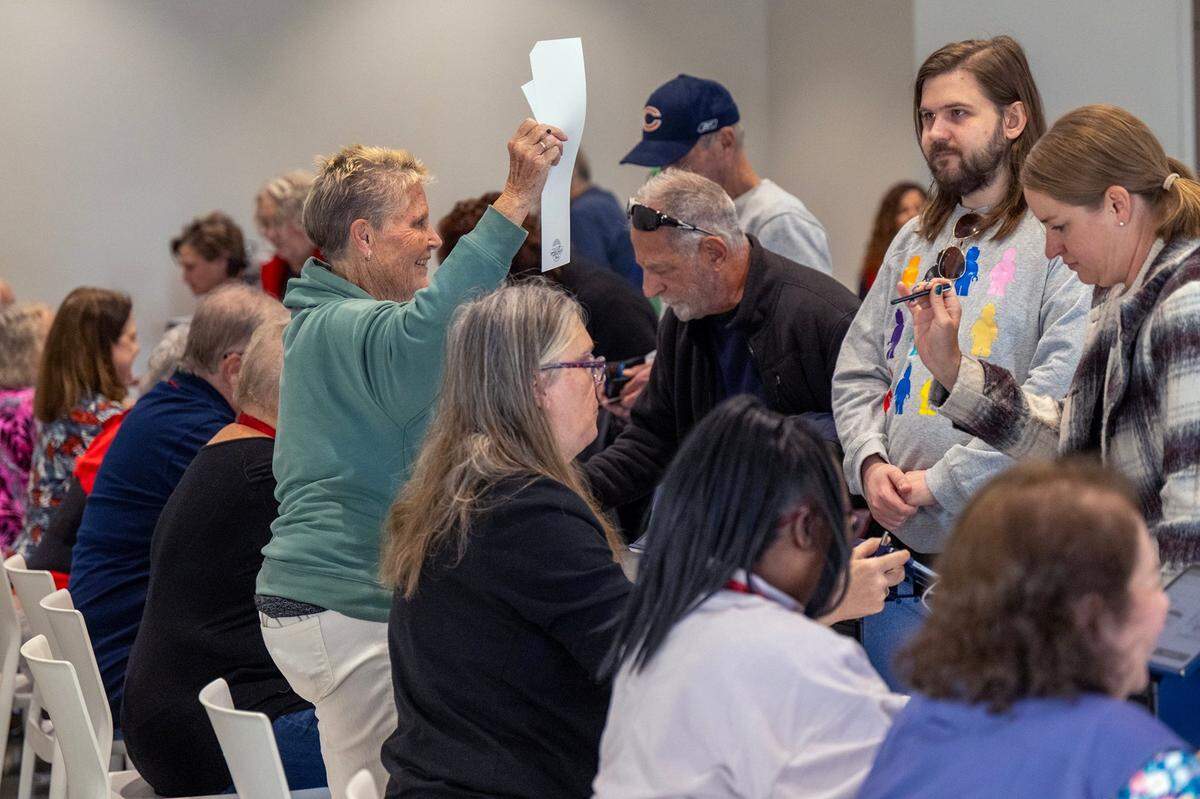 An election worker waved a ballot as Johnson County residents turned out for the first day of in-person advance voting for the 2024 General Election at The Arts and Heritage Center on Oct. 19, 2024, in Overland Park.