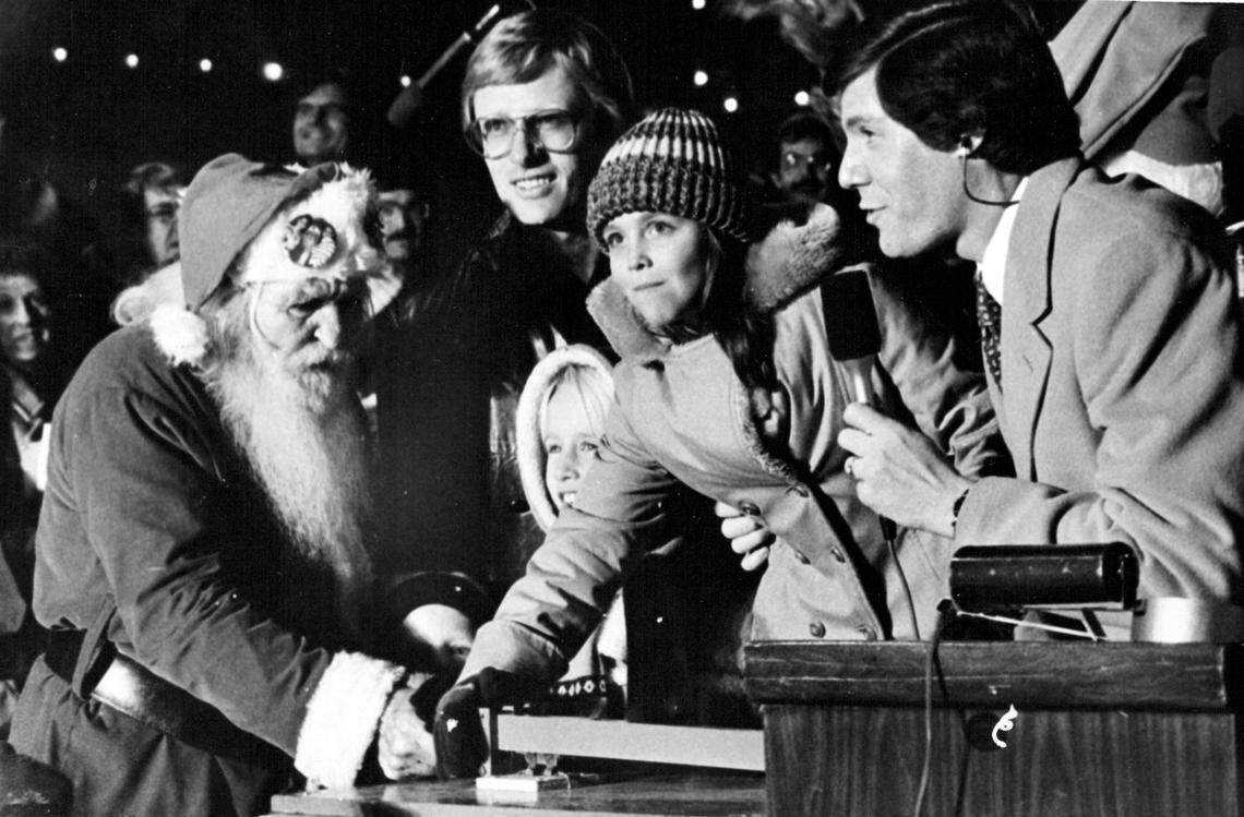 Angela O’Brien of Independence lights up the night as she throws the switch to illuminate the Plaza Christmas lights in 1978, with help from anchorman Scott Feldman (right), Royals pitcher Paul Splittorff (background), and an unidentified friend with a beard. An estimated 100,000 people gathered Thursday to welcome the holiday season.