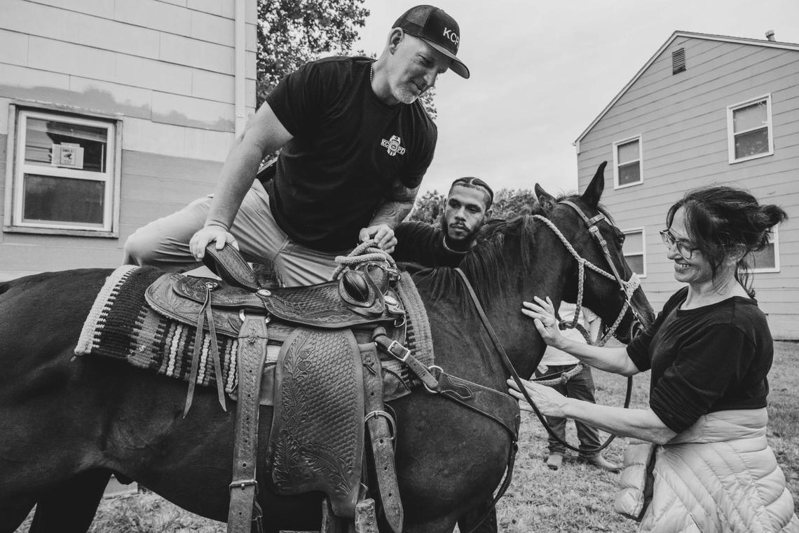 Officer David McKinzie mounts a horse as Isaiah Briscoe, aka CB Zay, assists, during a community outreach ride with KCPD in Kansas City. “The people know us, so when they see us with the police, they think, ‘Oh, the police have to be cool,’” says Simeon Brooks, one of the Copper Boyz.