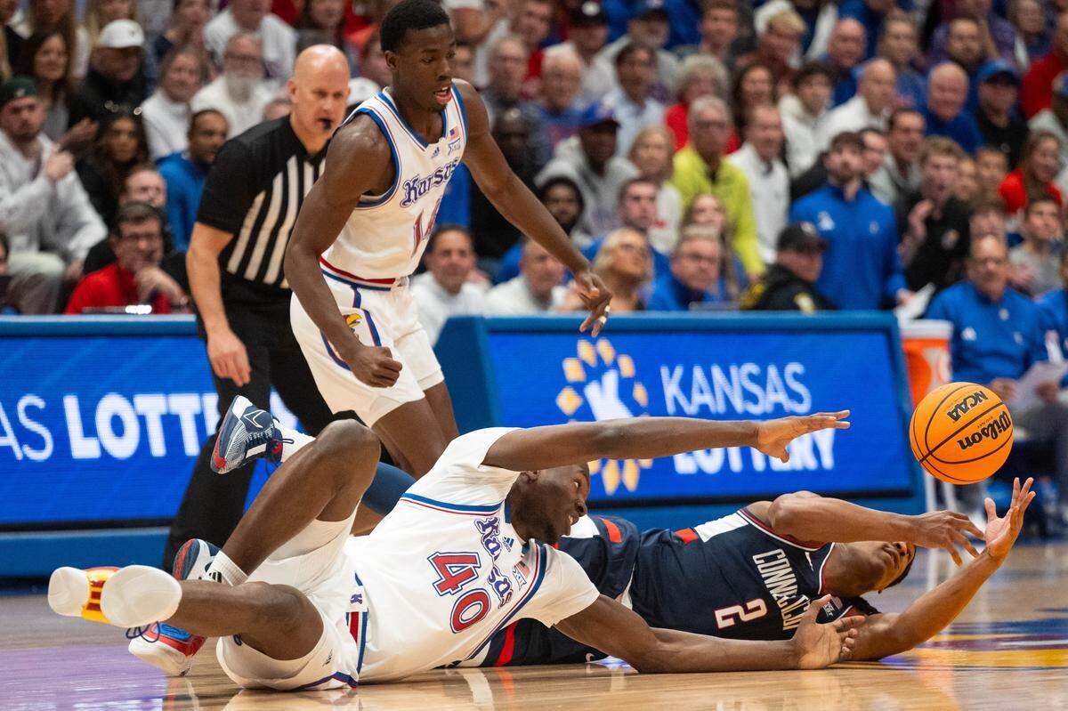 Kansas Jayhawks forward Flory Bidunga (40) scrambles for a loose ball against UConn Huskies guard Silas Demary Jr. (2) in the first half on Tuesday, December 2, 2025, at Allen Fieldhouse.
