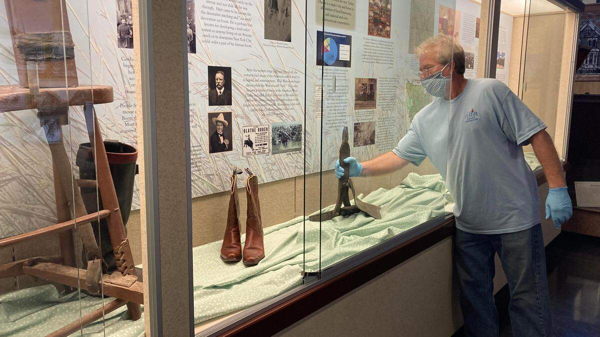 Tim Talbott, site manager for the Mahaffie Stagecoach Stop and Farm, places a plowshare in the “From Rodeos to Roundabouts: Exploring Olathe’s Roots” exhibit.