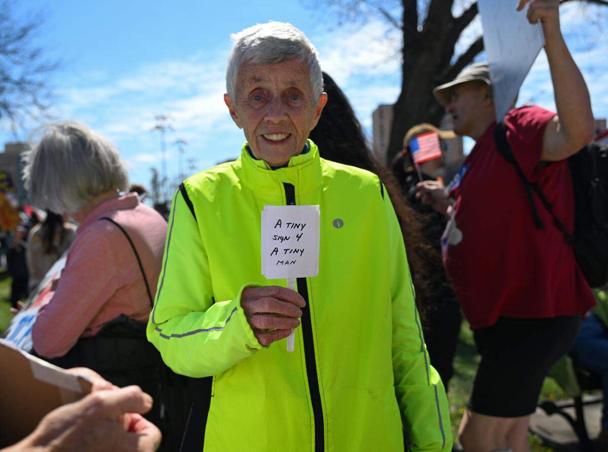 Anne Coveney holds up a “tiny” sign at a No Kings protest against the Trump administration in Mill Creek Park near the Country Club Plaza on Saturday, March 28, 2026, in Kansas City.