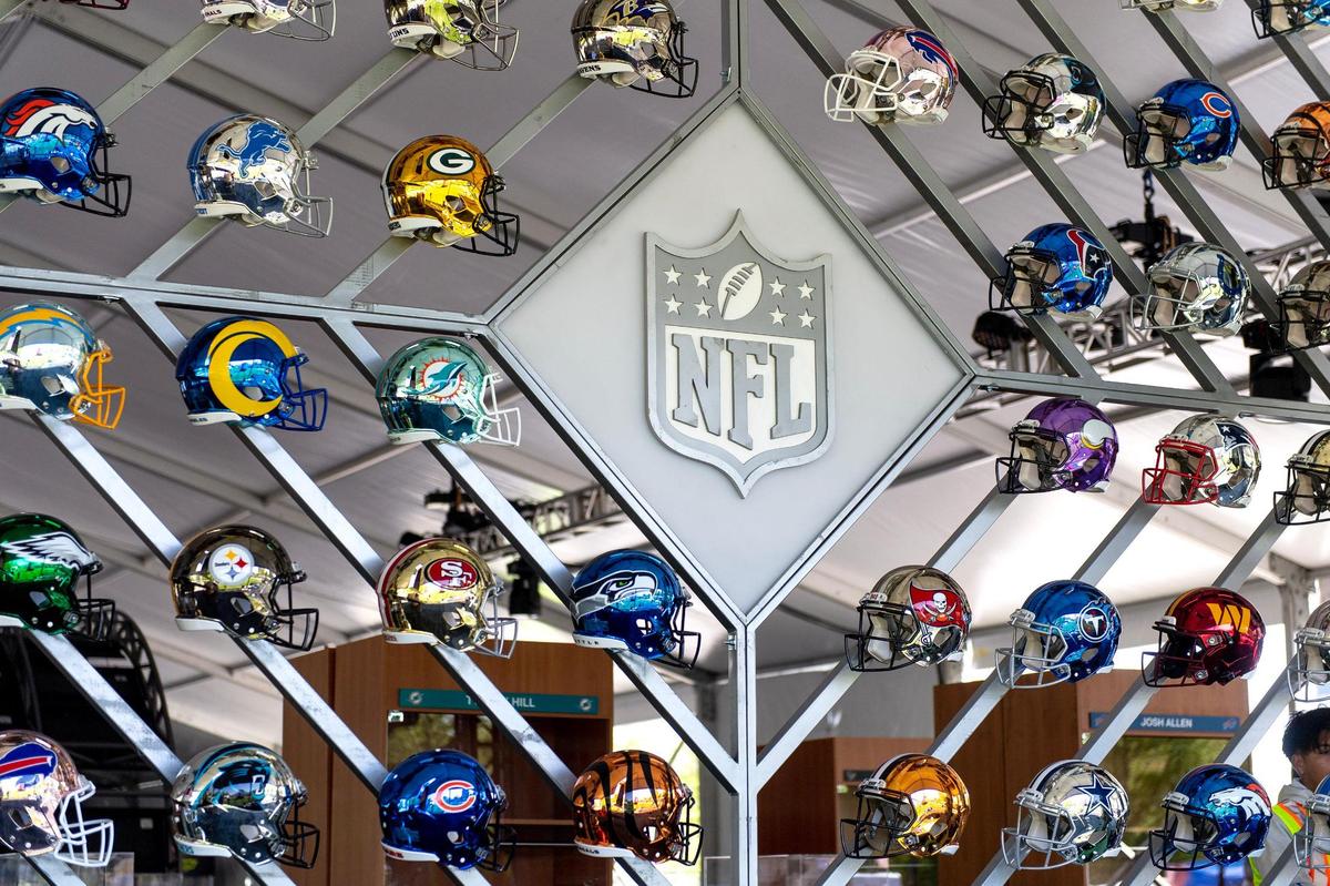 A wall of helmets displays each of the NFL’s 32 teams at the NFL Draft Experience tent on Tuesday in Kansas City.