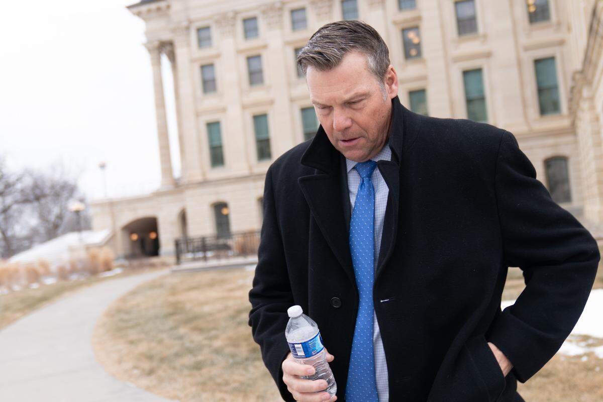 Kansas Attorney General Kris Kobach hunches outdoors