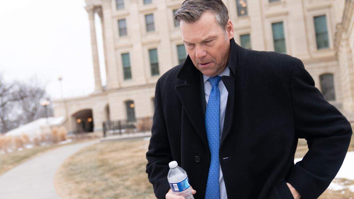 Kansas Attorney General Kris Kobach hunches outdoors