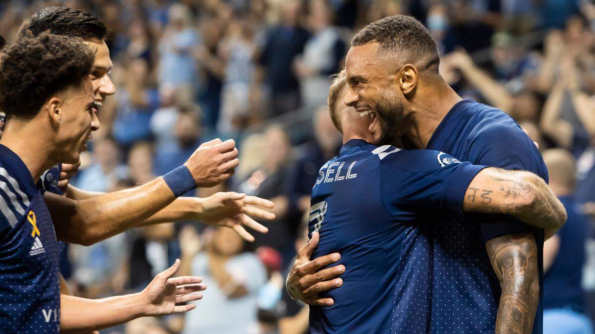 Sporting Kansas City forward Khiry Shelton, right, hugs forward Johnny Russell and celebrates with other teammates after scoring against the Minnesota United on Wednesday at Children’s Mercy Park in Kansas City, Kan.
