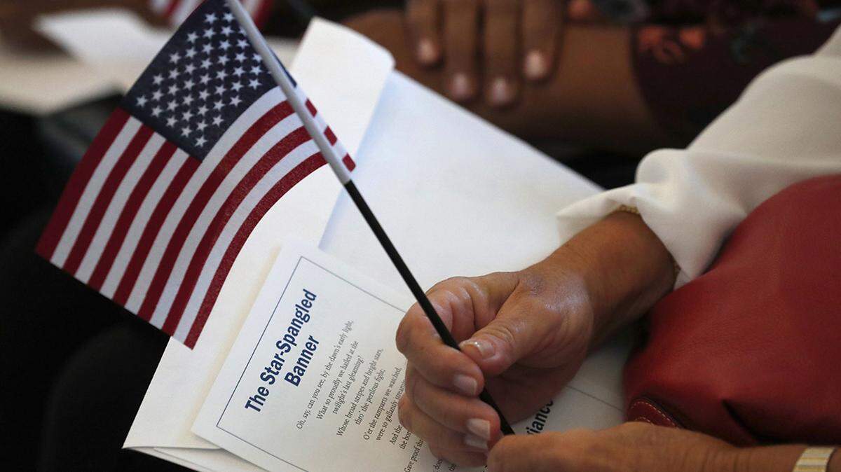 In this file photo, a citizen candidate holds an American flag and the words to The Star-Spangled Banner before the start of a naturalization ceremony at the U.S. Citizenship and Immigration Services field office in Miami.