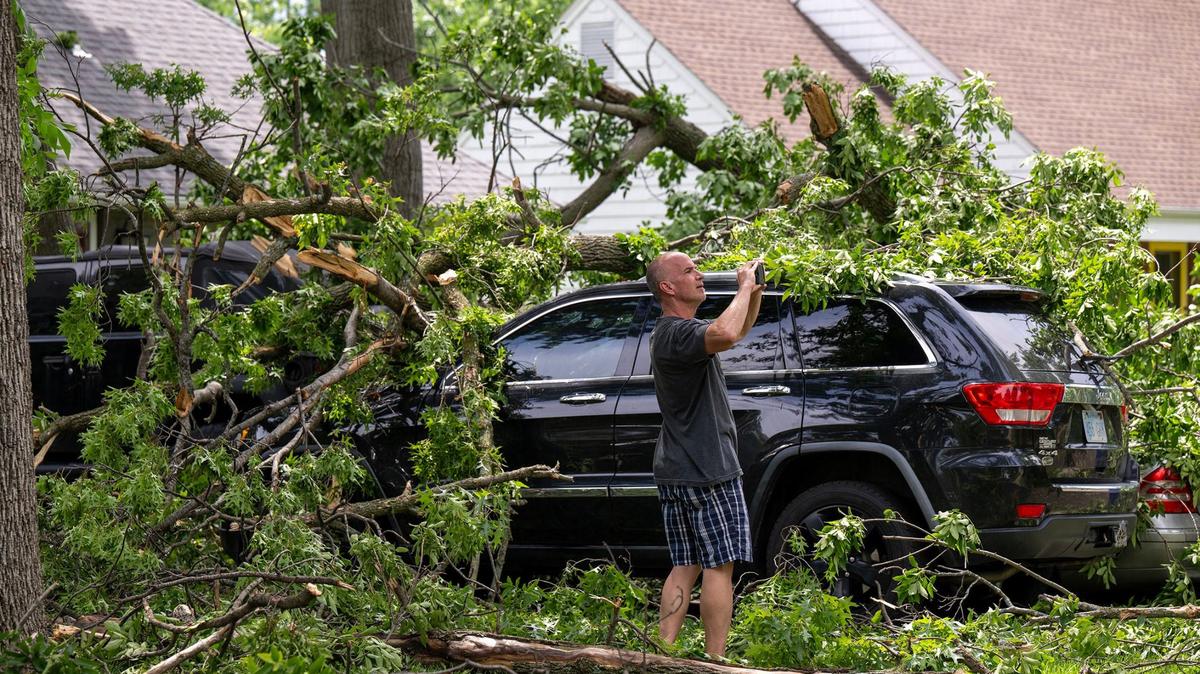 Dave Basile of Overland Park used his cell phone to record storm damage after a late night storm with strong winds moved through the 8700 block of Conser Street Sunday night bringing down trees and power lines. Basile looked over the damage, including his neighbors’ house and three cars that were covered in tree limbs Monday in Overland Park. Basile’s house was mostly spared any damage.