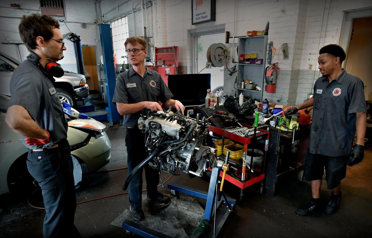 Tom Keegan, center, owner of Hyde Park Auto Service, goes over a recent repair to a Toyota engine with mechanics Josef Koukol, left, and Jovanni Hamilton.