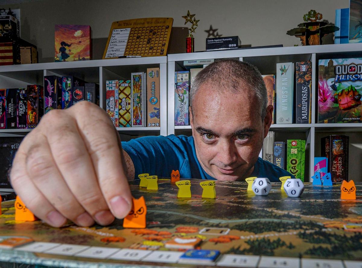 Steve Burrows shows one of his favorite games, Root, at his home in Lee’s Summit. Every Saturday he and his wife host a game day with friends.