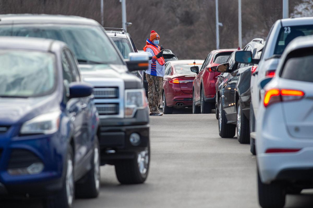 Volunter Ted Stipanovich directed vehicles in and out of the parking lot Friday at Cerner World Headquarters for Clay County’s first mass COVID-19 vaccine clinic. Area health departments and hospitals are signing up people online for future vaccinations.