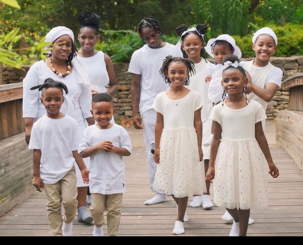 Danielle Benson, left in a white head wrap, and her eight children have been without her oldest child, Aaron Williams, center, for a month after he was killed in a July shooting outside an apartment complex.