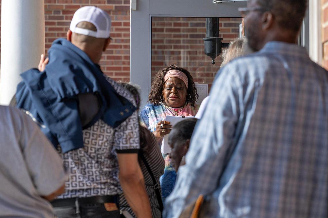 A DMV employee calls out numbers for customers waiting in line outside the Kansas City DMV on Wednesday, May 7, 2025, in Kansas City. The office reached capacity early in the morning as people waited to apply for Real IDs.