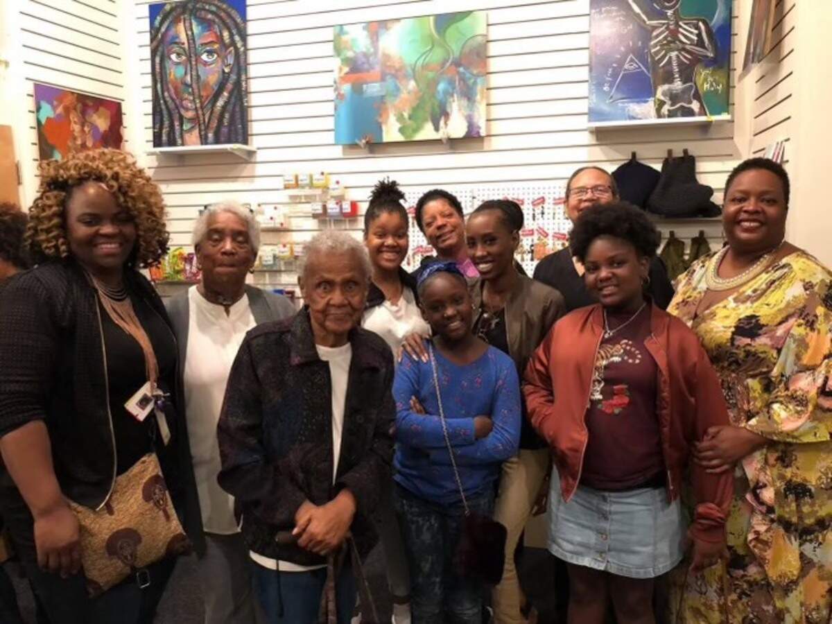 Juanita Gibson seen at an art show with her work and five generations of decendants.