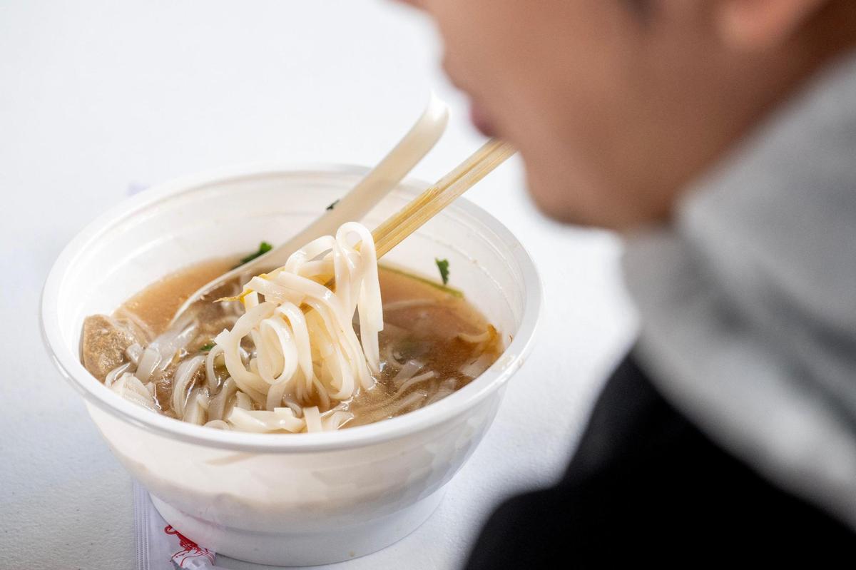 A visitor eats a bowl of pho at Taste of AAPI festival.
