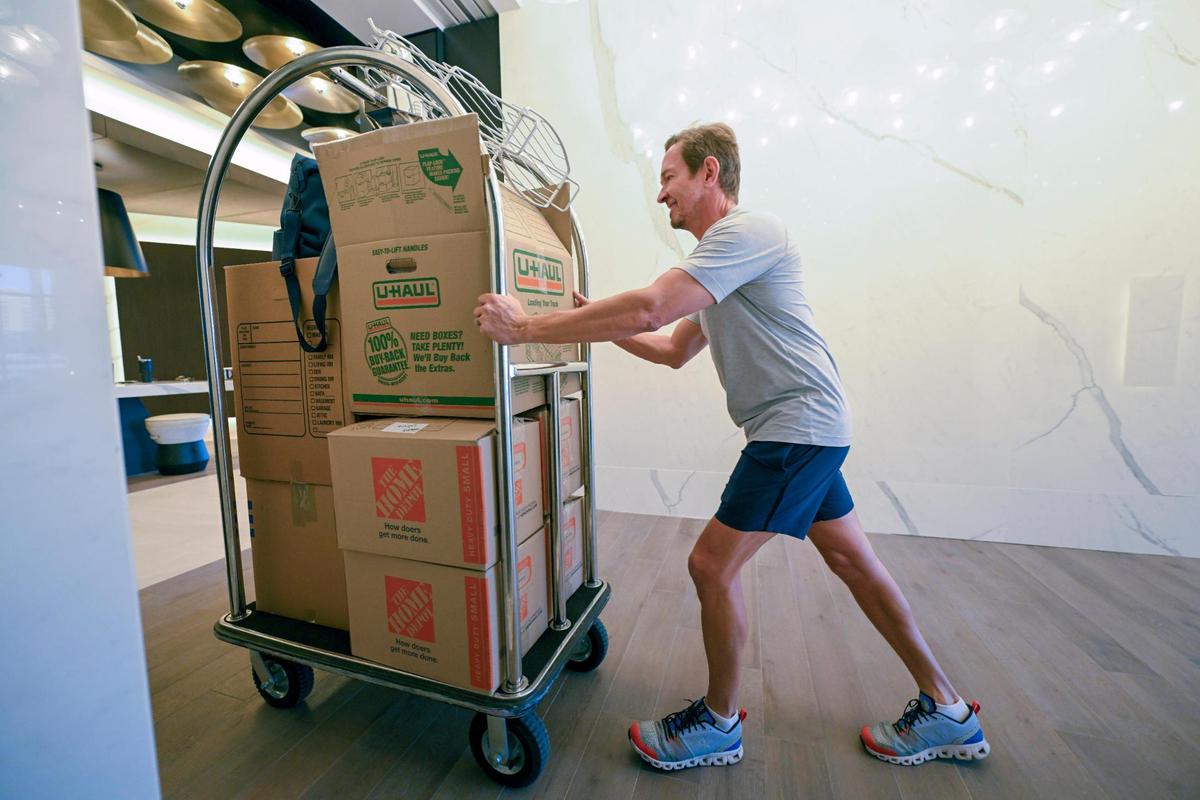 Tony Patton pushes a luggage cart of belongings to his new apartment at the Three Light Luxury Apartments. Tony and his wife, Tiffany Patton, moved into Three Light after living in the Two Light building since it opened about five years ago. The pair own businesses within walking distance of Three Light.