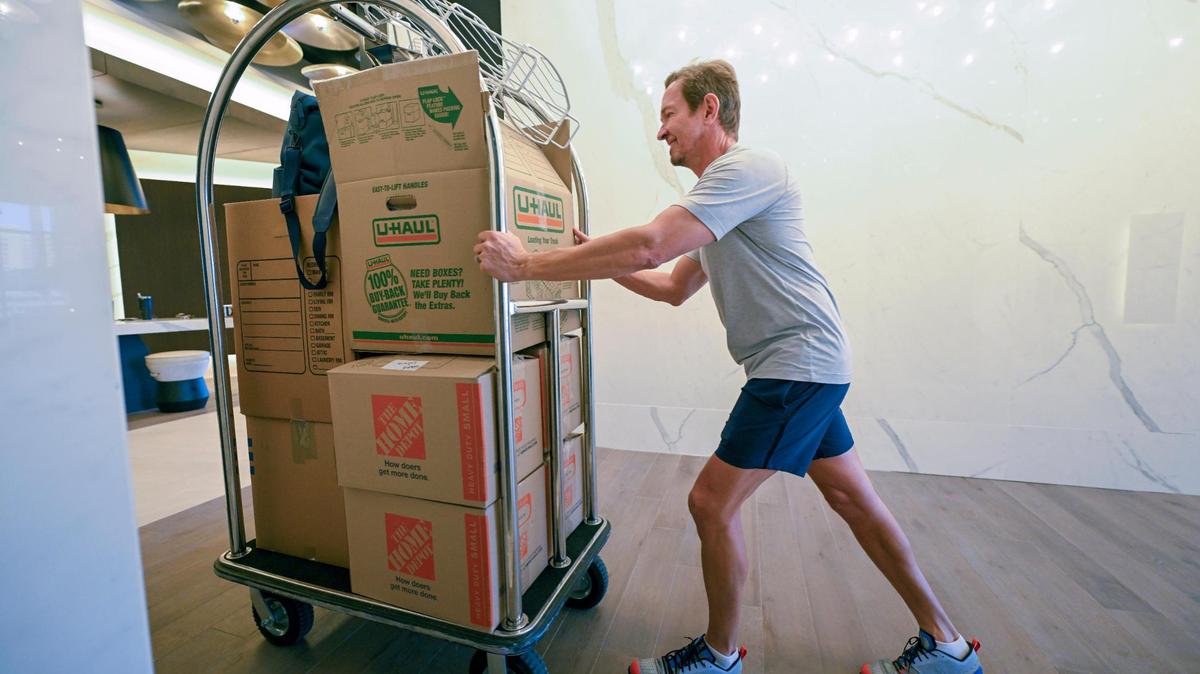 Tony Patton pushes a luggage cart of belongings to his new apartment at the Three Light Luxury Apartments on Wednesday, Sept. 13, 2023 in Kansas City. Tony and his wife, Tiffany Patton, moved into Three Light after living in the Two Light building since it opened about five years ago. The pair own businesses within walking distance of Three Light.