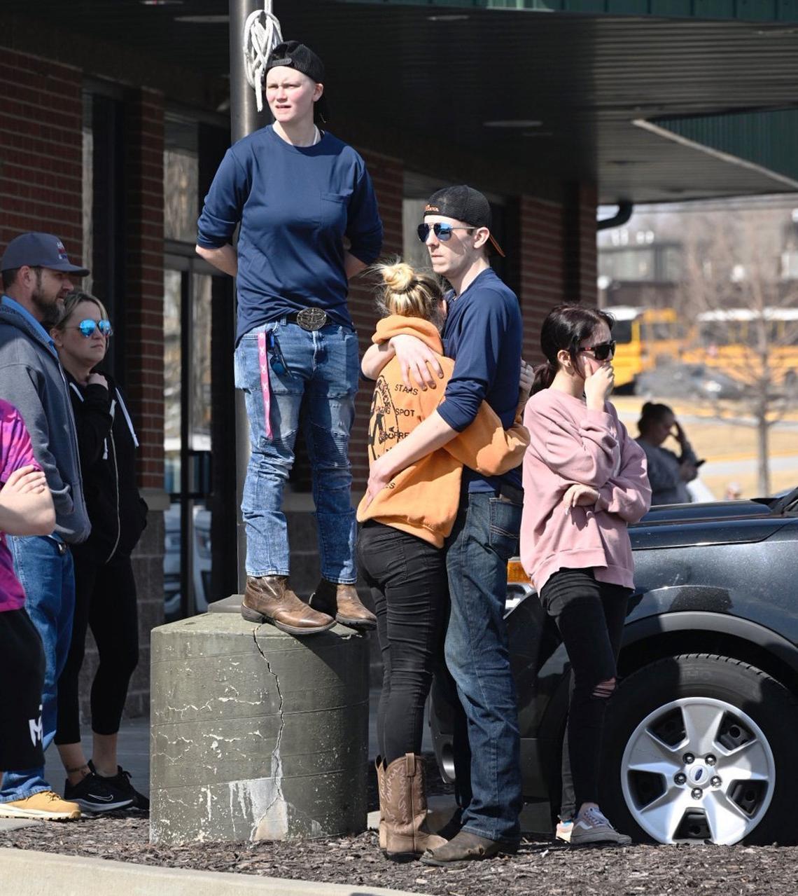 Joe Kathrens, who was hugging Morgan Montgomery, and Skyler Pattullo, on the light post, waited at the site near 127th Street and South Black Bob Road, where parents could reunite with their children after the March 4 shooting at Olathe East High School. They live nearby and have friends at the school.