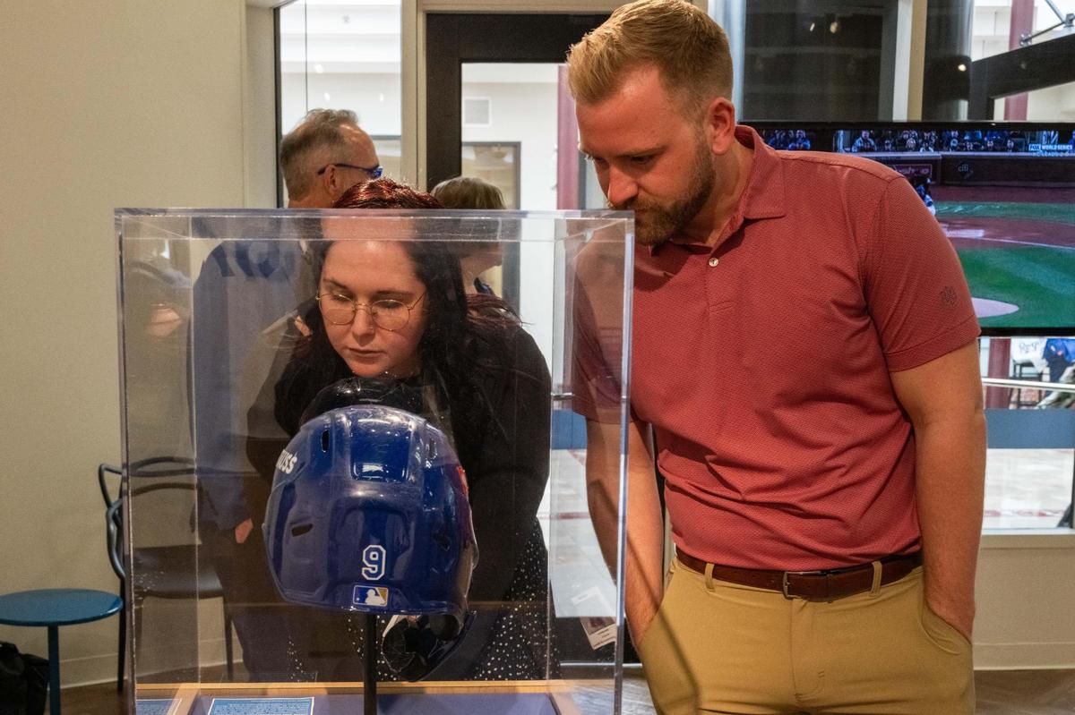 Shianne Kolts and Cole Reser take a look at Royals first baseman Vinnie Pasquantino’s game worn helmet at the Royals’ Crowning Achievements Exhibit at Commerce Bank in downtown Kansas City on Tuesday.