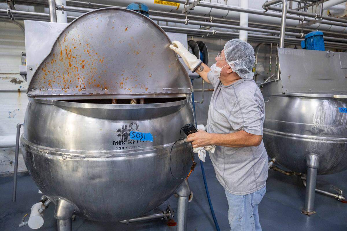 An employee of Spicin Foods lifts the lid on a boiler full of sriracha hot sauce, on October 2, 2025, at the Spicin Foods warehouse on Southwest Boulevard, in Kansas City. Spicin Foods not only makes their own sauces but also serves as a maker and bottler of other well-known sauces on the market.