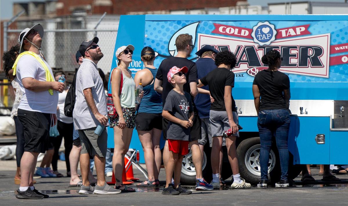 People gawk at planes flying as they wait to use a water station during the Garmin KC Air Show on Saturday, Aug. 19, 2023, in New Century, Kan.