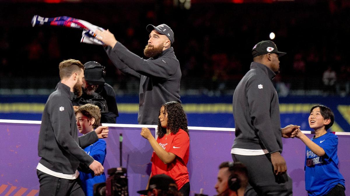 Kansas City Chiefs tight end Travis Kelce waves a towel as defensive tackle Chris Jones, right, and place kicker Harrison Butker greet young fans during Super Bowl LVIII’s Opening Night event at Allegiant Stadium on Monday, Feb. 5, 2024, in Las Vegas.