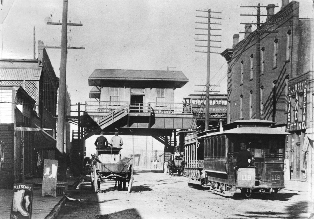 An elevated railroad, which connected Kansas City, Mo., the old Union depot in the West Bottoms, and Kansas City, Kansas, was the most up-to-date transit system in its day. Shown is the Mulberry street station at Ninth and Mulberry with an electric street car pulling in from the east. A cable train proceeds north on Ninth. The picture was taken in the early 1890s.