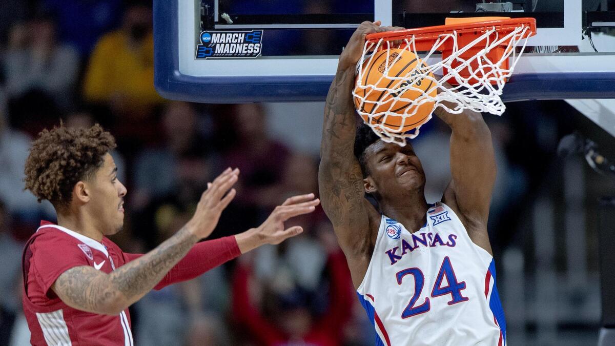 Kansas forward K.J. Adams Jr. dunks the ball as Arkansas forward Jalen Graham defends during a second-round college basketball game in the NCAA Tournament on Saturday, March 18, 2023, in Des Moines, Iowa.