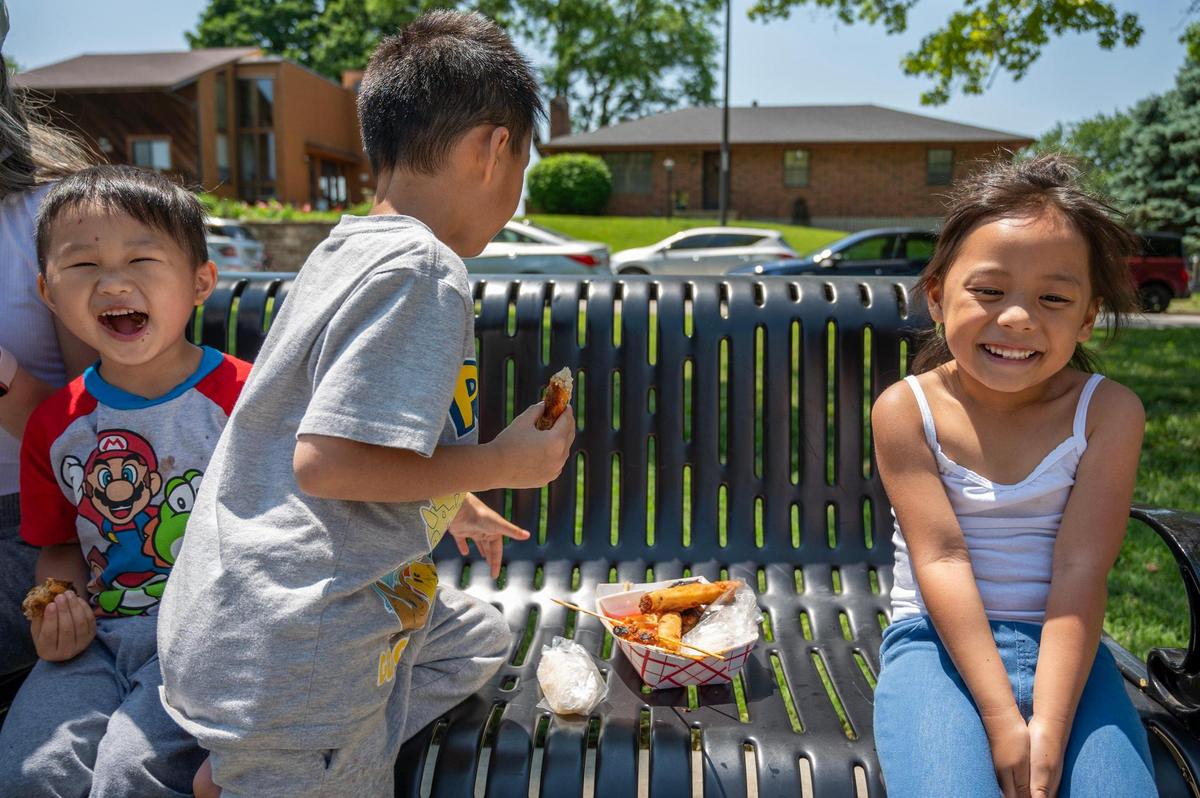 Four-year-old Jaxxon Chamblerlin, left, and four-year-old Estelle Cha laugh together while eating food from Laos House during the AAPIconic Festival on Saturday, May 20, 2023, in Kansas City.