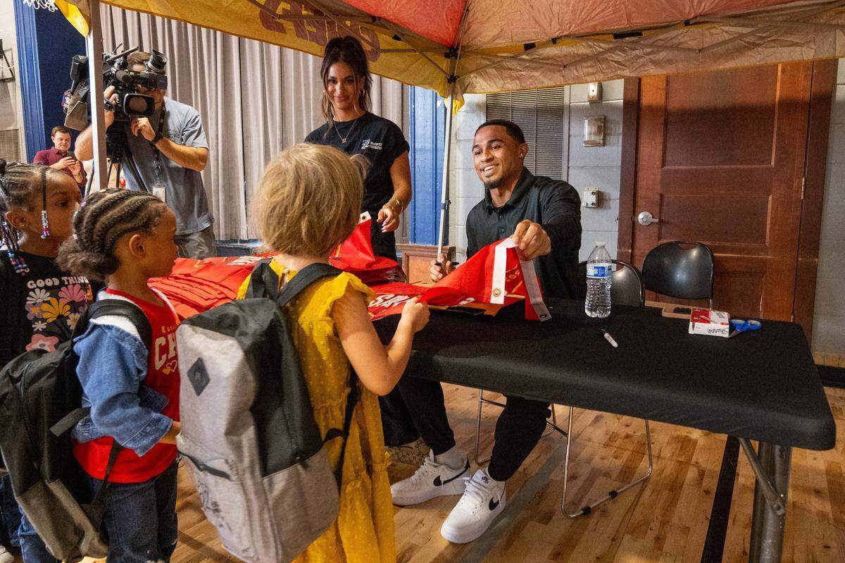 Kansas City Chiefs cornerback Trent McDuffie signs a Chiefs flag for students at Gordon Parks Elementary School.