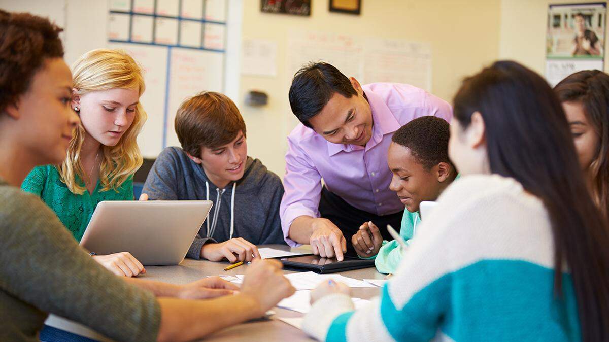 High School Students With Teacher In Class Using Laptops classroom educator education teach