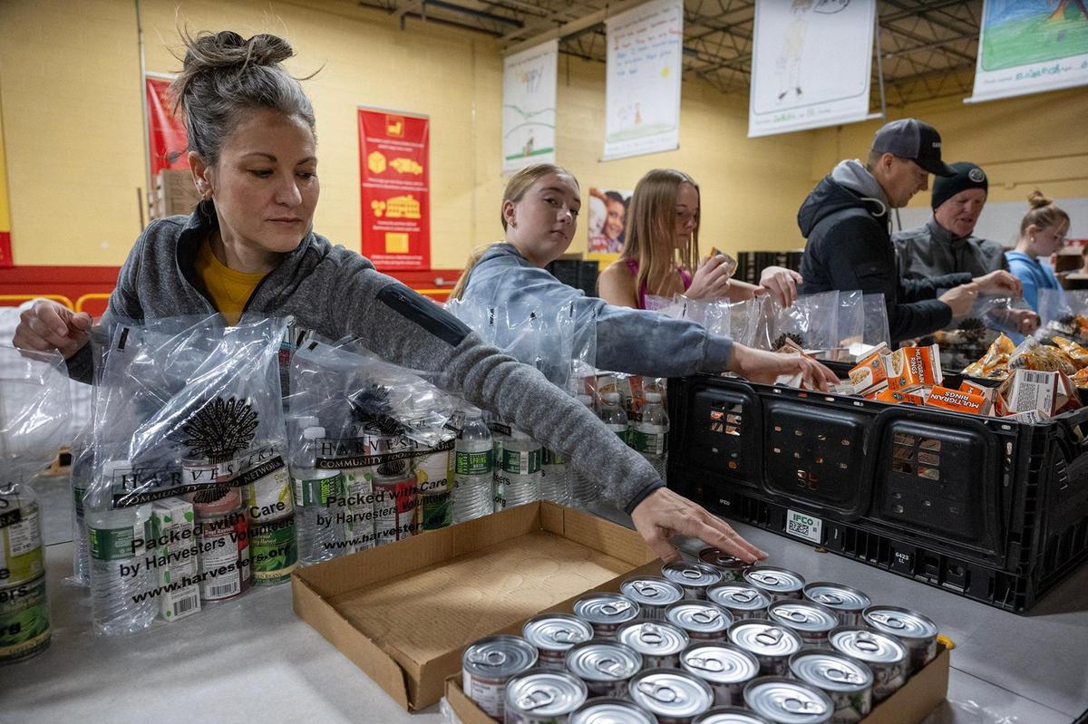Volunteers Meagan Witkowski, left, of Overland Park, her daughter, Audrey Witkowski, 13, and Emme Walker, 14, of Kansas City packed BackSnacks at Harvesters on the MLK Day of Service on Monday, Jan. 20, 2025, in Kansas City. The BackSnacks program provides food for elementary and some middles school students to take home over the weekend.