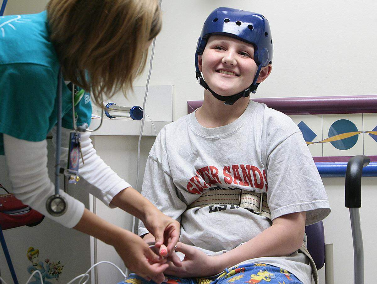 As Lage Grigsby smiles at his dad who was watching nearby, Children’s Mercy Hospital nurse Sarah Lovejoy takes his vital health information during surgery check-in. Lage, 14, was near death after the tornado pulled him from his grandpa’s truck. On July 5, 2011, surgeons planned to put Lage’s skull back together using bone doctors stored in his stomach to keep it alive.