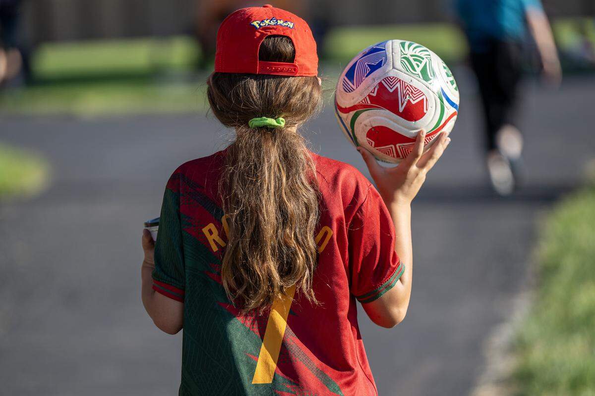 An attendee wearing a Cristiano Ronaldo jersey holds a soccer ball while walking near the North Lawn of the National WWI Museum and Memorial during the Kansas City Symphony's annual Celebration at the Station concert at Union Station on Sunday, May 24, 2026, in Kansas City.