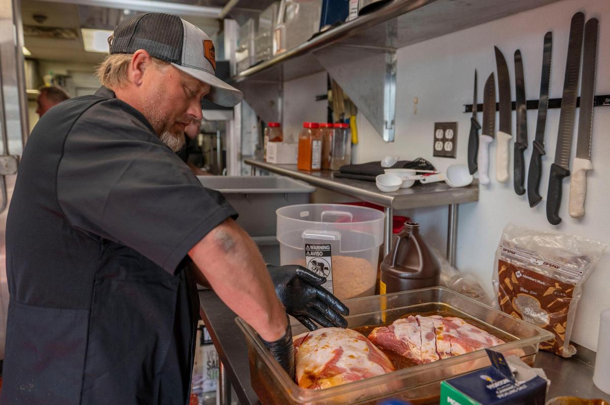 James Huey, co-owner at F325 BBQ, coats pork shoulder with a house-made marinade.