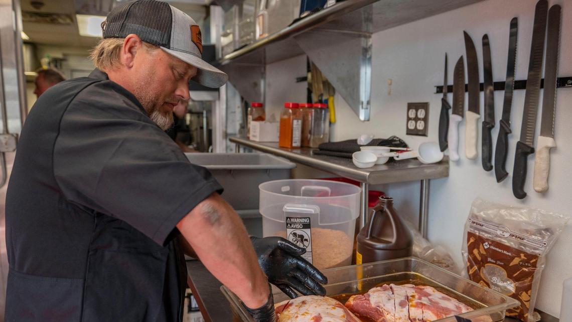 James Huey, co-owner at F325 BBQ, coats pork shoulder with a house-made marinade.