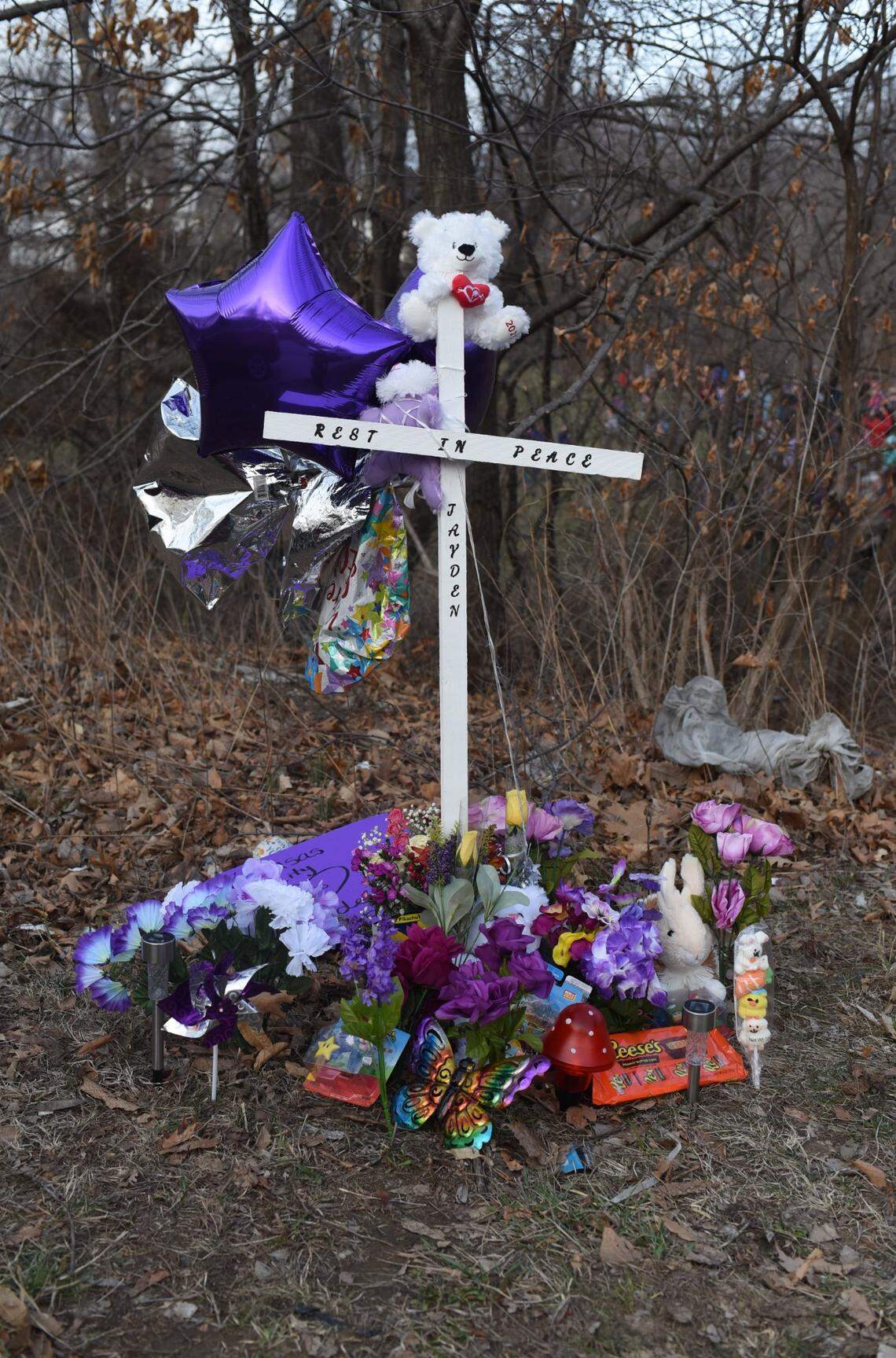 A cross sits surrounded by tributes to Jayden Robker, a missing Kansas City 13-year-old whose body was found Friday in a pond in Gladstone. Robker had been missing since early February