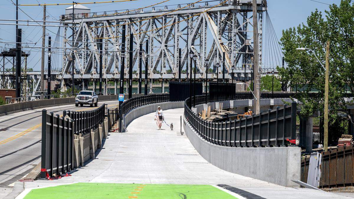 A person walks a dog along the Grand Boulevard Pedestrian/Bike Bridge on Monday, April 20, 2026, in Kansas City.