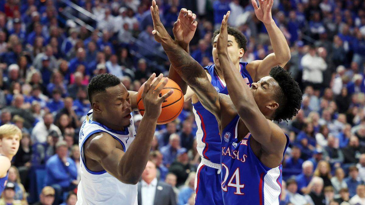 Kentucky’s Oscar Tshiebwe, left, is defended by Kansas’ K.J. Adams (24) and Kevin McCullar Jr., middle, during the first half of a game in Lexington, Ky., Saturday, Jan. 28, 2023.