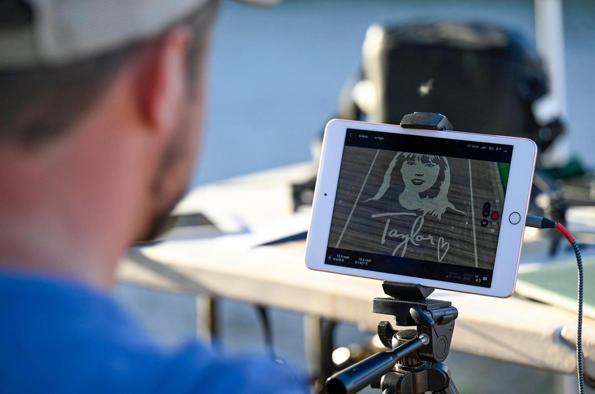 A member of the drone team monitors the video being shot as Rob Stouffer of Precision Mazes, cuts a welcome message to Taylor Swift in a field of wheat stubble on Monday, July 3, 2023, in Orrick, Missouri.