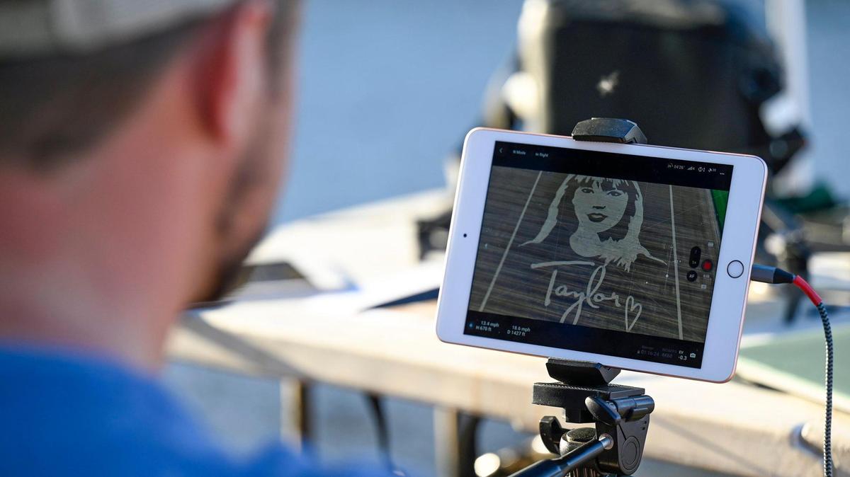 A member of the drone team monitors the video being shot as Rob Stouffer of Precision Mazes cuts a welcome message to Taylor Swift in a field of wheat stubble on July 3, 2023, in Orrick, Missouri.